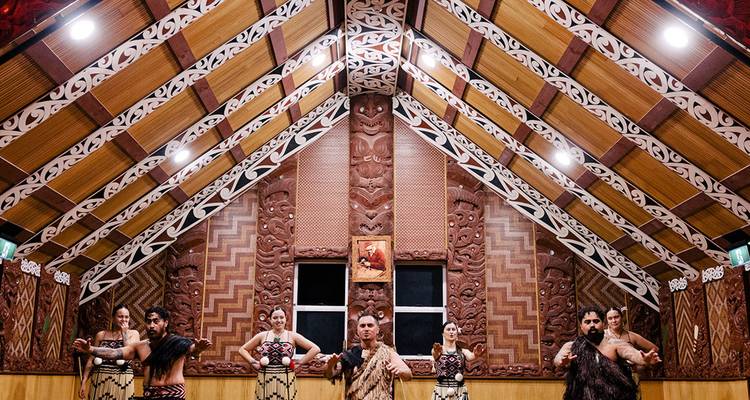 Spectacle culturel maori à l'intérieur d'une salle richement décorée.