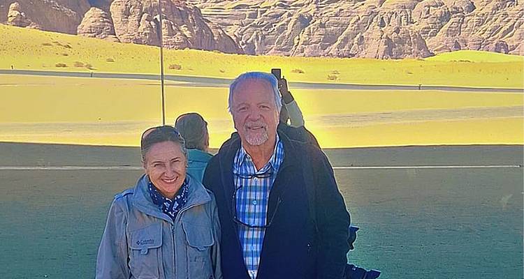 Older couple with sandy desert backdrop.