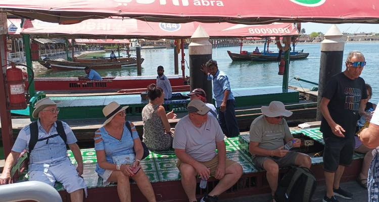People sitting on a traditional abra boat with a waterfront view.