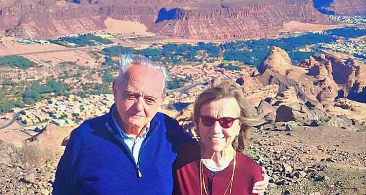 Elderly couple smiling with a rocky landscape behind them.