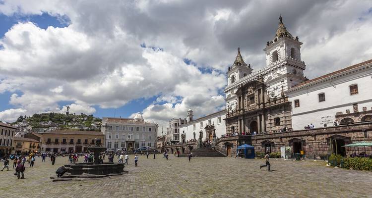 Busy plaza with historical buildings and people gathered around.