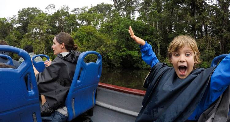 Family enjoying a boat ride through a rainforest.