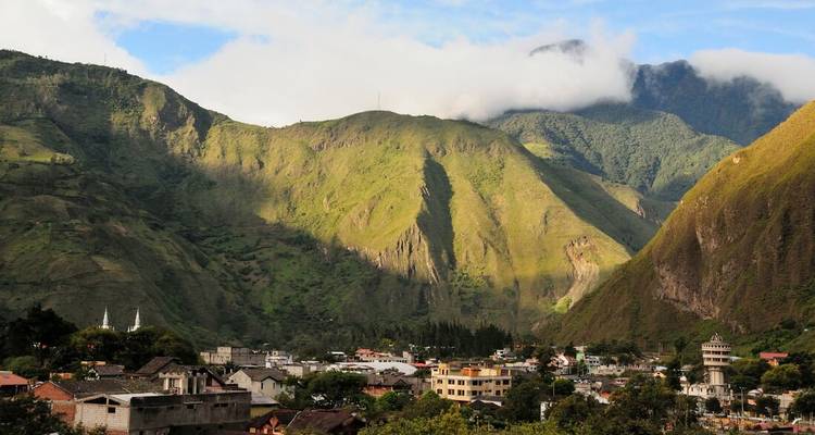 Un pueblo enclavado entre exuberantes colinas verdes bajo un cielo nublado.