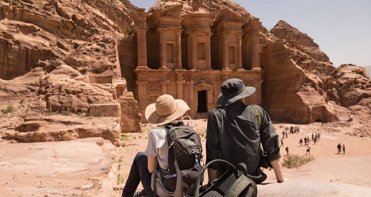 Des visiteurs avec des sacs à dos assis au Monastère de Pétra.