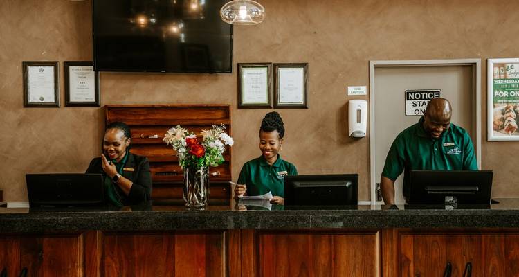 Three people at a hotel reception desk smiling.