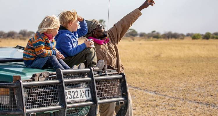 Begeleide safari met kinderen in een voertuig in de savanne.