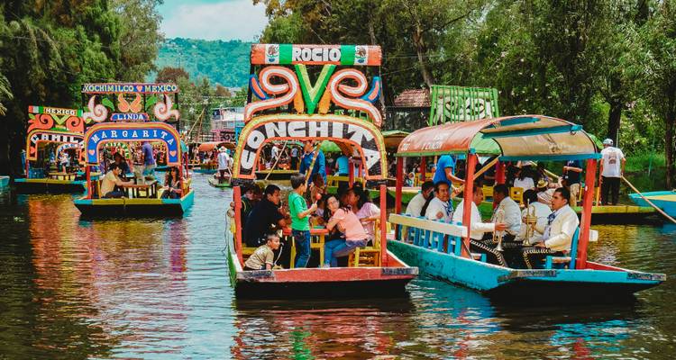 Colorful trajinera boats filled with people enjoying canal cruise at Xochimilco.