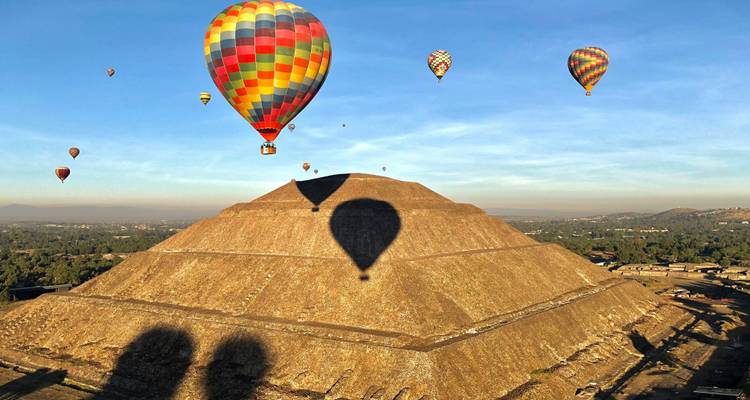 Hot air balloons floating over Pyramid of the Sun at Teotihuacan at sunrise.