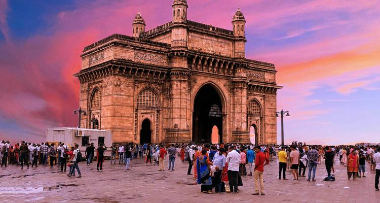 Porte de l'Inde avec une foule animée et un ciel coloré.