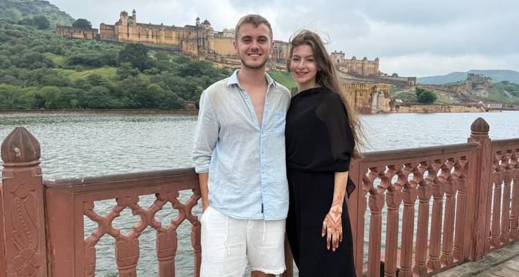 Un couple profitant de la vue depuis un pont avec un fort historique visible de l'autre côté de l'eau.