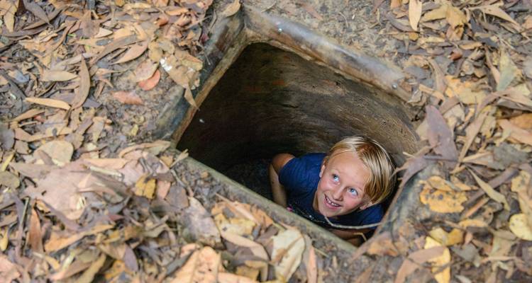 Child looking out of a small underground tunnel entrance.