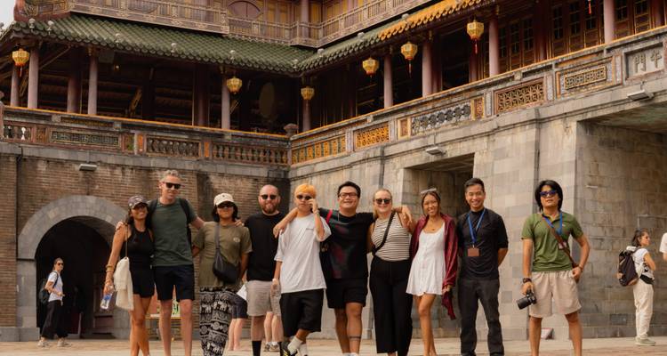 Grupo de turistas sonriendo alineados frente a la puerta de entrada de la ciudadela imperial de Hué