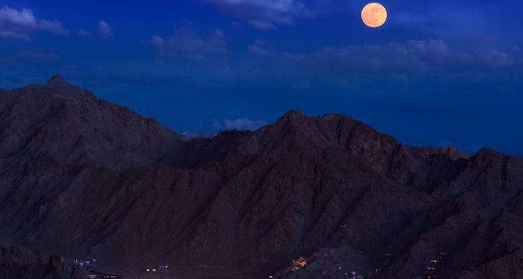 Full moon over mountain range at night.