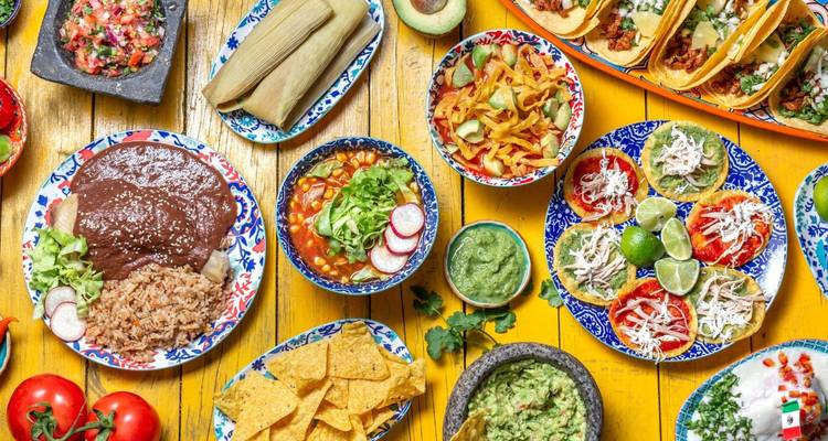 Kleurrijke selectie van traditionele Mexicaanse gerechten met tacos, tamales en salsas op een levendige houten tafel