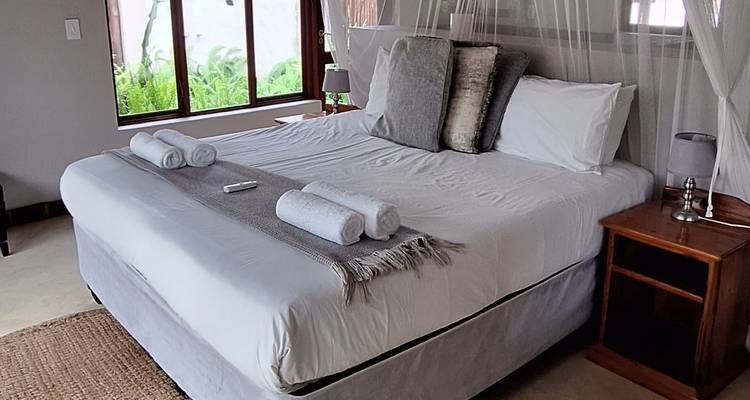 Chambre d'hôtel soigneusement préparée avec un grand lit, des draps blancs et des serviettes roulées.
