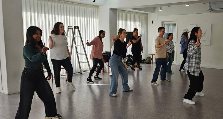 Travelers practice dance moves in a bright studio during a K-pop lesson.