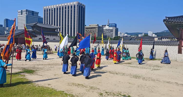 Traditional guard changing ceremony with performers in colorful hanbok in Gyeongbokgung Palace courtyard.
