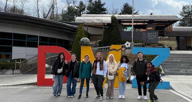 Travelers pose beneath large colorful DMZ letters at the Korean demilitarized zone visitor area.