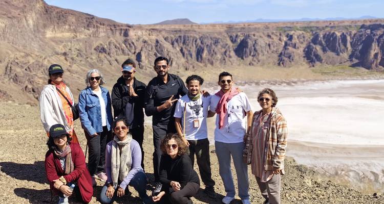 Group of tourists with a desert crater in the background.