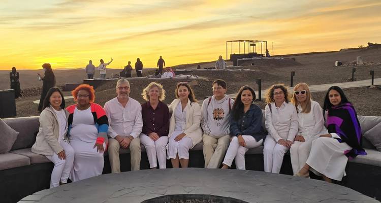 Group of people sitting together at sunset with a scenic view in the background.