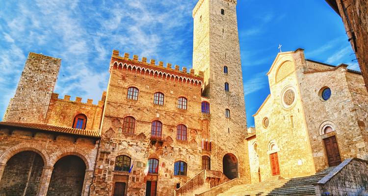 Historic town square with stone buildings and blue sky.