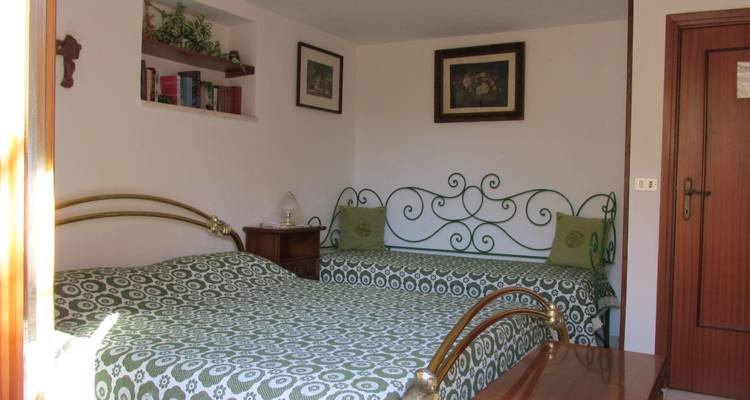 Chambre d'hôtes douillette avec lit double, literie verte à motifs et tête de lit en fer forgé.