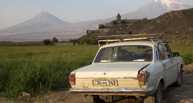 Altes sowjetisches Auto mit Blick auf einen Berg und eine Festung.