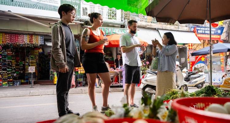 A small group of people interacting with a local vendor at an outdoor market.
