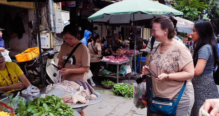 People browsing through fresh produce at a lively outdoor market.