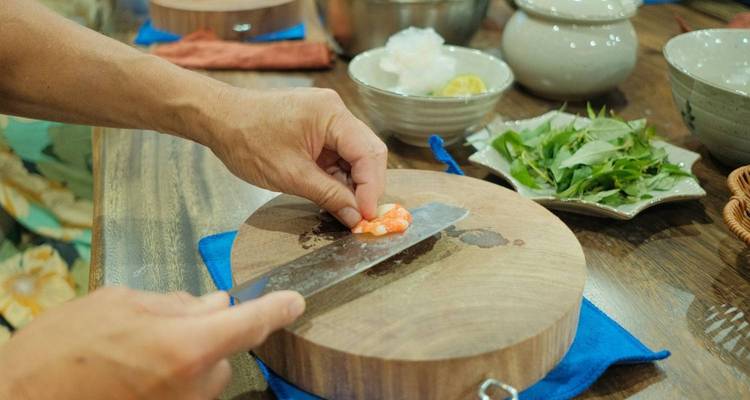 Close-up image of hands preparing shrimp on a cutting board in a kitchen.