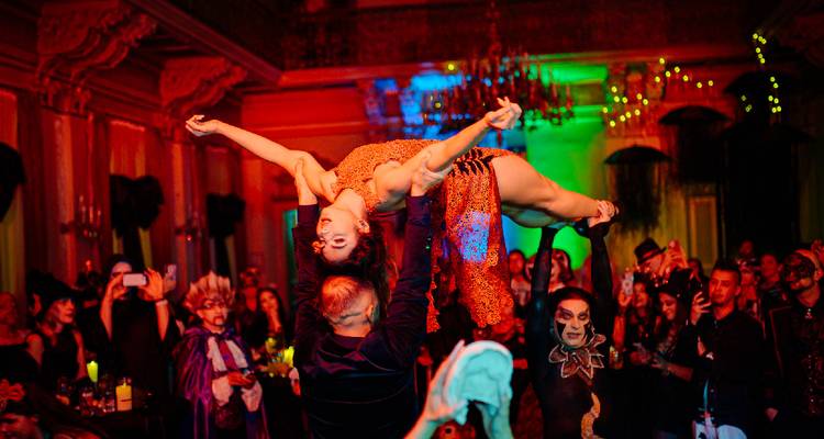 Artistes lors d'un événement costumé avec l'un tenant l'autre au-dessus de la foule dans une pose dramatique.