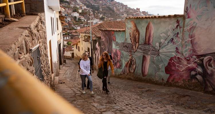 Des gens qui remontent une rue pavée avec des peintures murales.