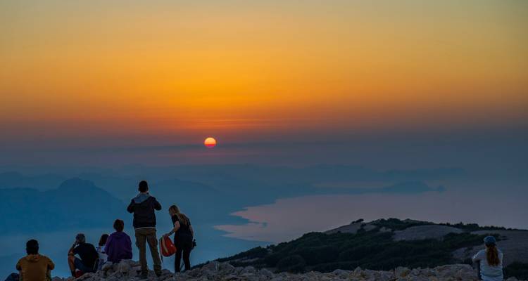 People watching a scenic sunset from a high viewpoint.