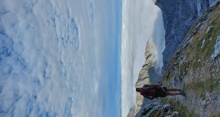 A person hiking along a mountain ridge above the clouds.