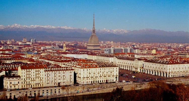 Cityscape view of Turin with the Mole Antonelliana and the Alps in the background.