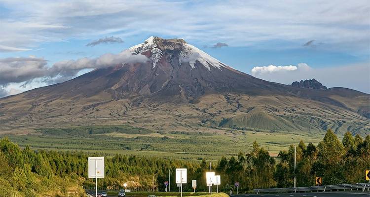 Le majestueux volcan Cotopaxi s'élève au-dessus des forêts verdoyantes et des terres agricoles, couronné de neige fraîche.