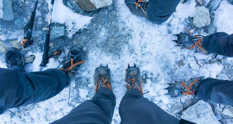 Les bottes munies de crampons des alpinistes se dressent sur la glace et la roche, les bâtons reposant à proximité avant l'ascension.