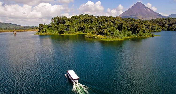 Vue panoramique d'un bateau sur un lac avec un volcan en arrière-plan.