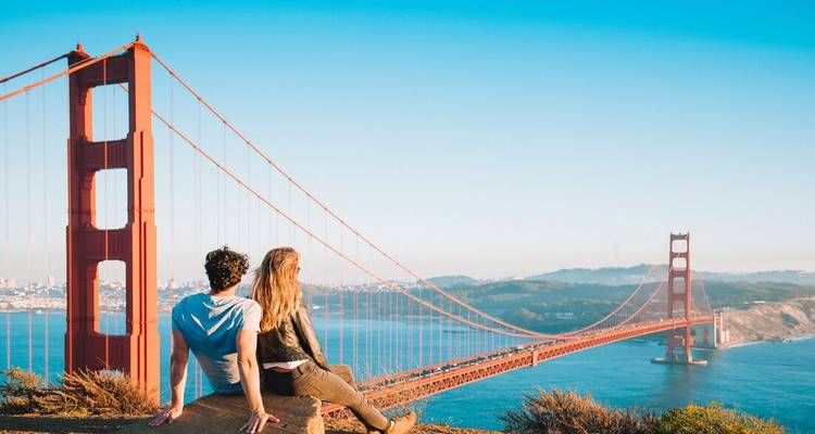 A couple sitting and admiring the Golden Gate Bridge.
