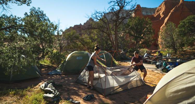Couple setting up a tent at a scenic camping spot.