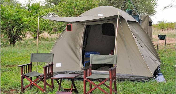 Zelt mit Stühlen, die draußen in einer grasbewachsenen Umgebung aufgestellt sind.