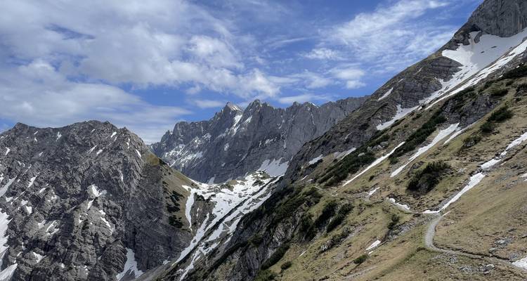 Chaîne de montagnes enneigée sous un ciel partiellement nuageux.