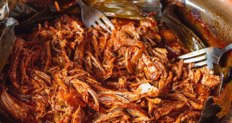 Close-up of traditional shredded pork pibil with forks.