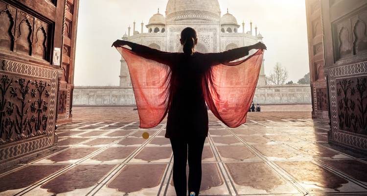 Silhouette einer Person, die vor dem Taj Mahal steht mit weit ausgebreiteten Armen.