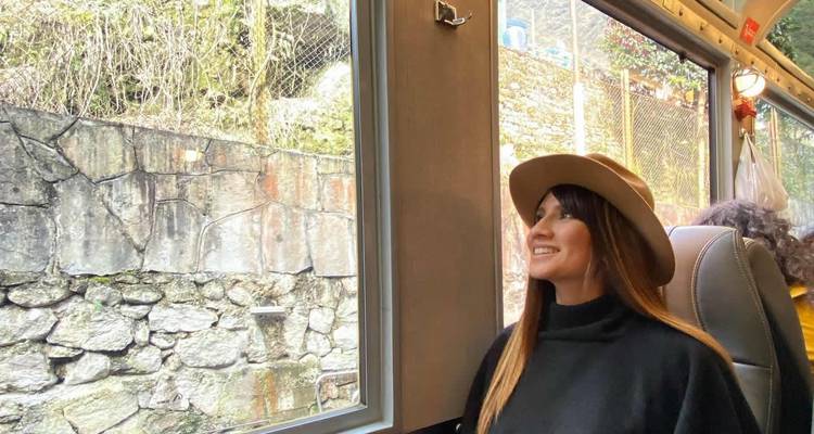 Une femme portant un chapeau assise dans un train regardant par la fenêtre.