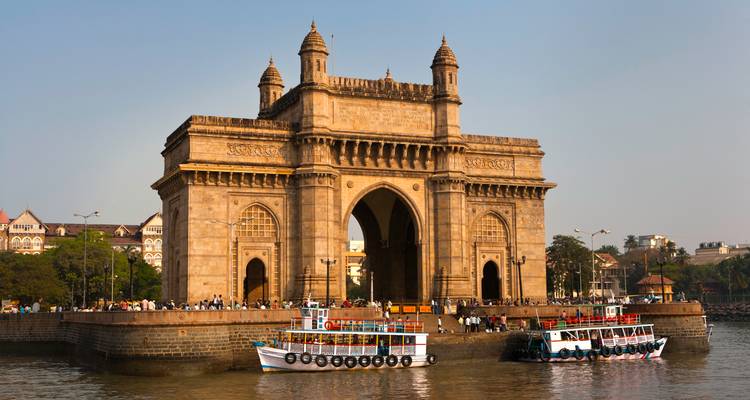 Gateway of India met boten op de voorgrond en mensen die het monument bezoeken in Mumbai, India.