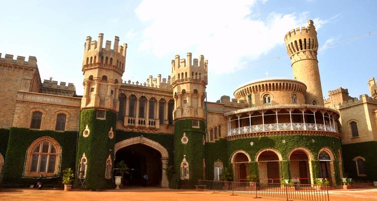 Entrance of the Bangalore Palace surrounded by lush greenery in India.