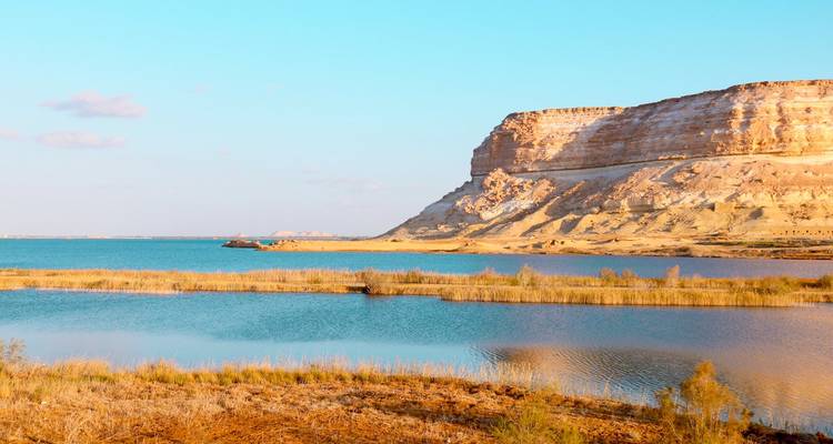Falaise à côté d'un grand lac ou réservoir dans un paysage désertique.