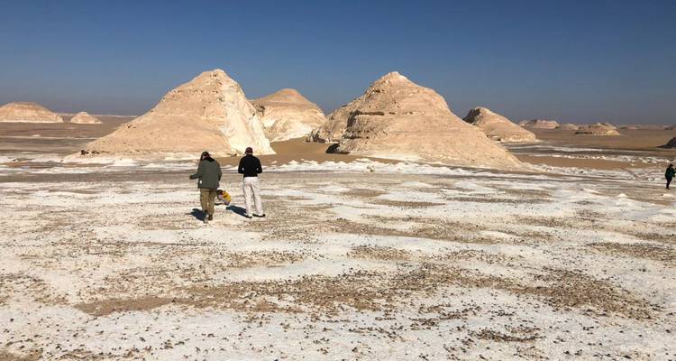 Deux personnes marchant dans un paysage désertique avec des formations rocheuses.