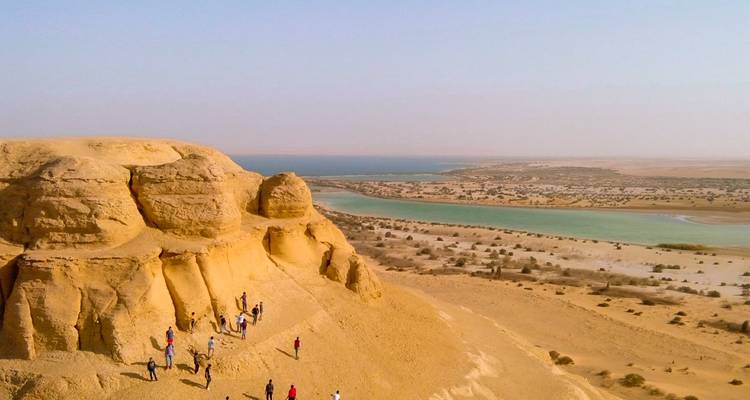 Groupe de personnes marchant le long du bord d'une falaise surplombant une rivière.